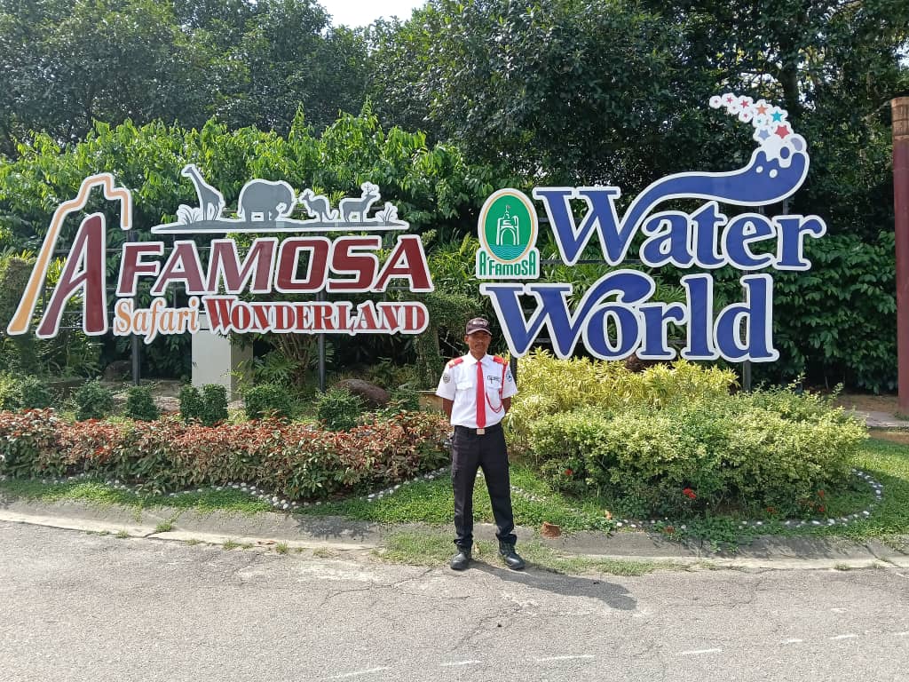KSD Security guard on duty before the A'Famosa Safari Wonderland and Water World signage surrounded by landscaped greenery.
