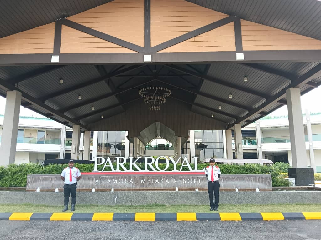 Two KSD Security guards flanking the PARKROYAL A'Famosa Melaka Resort entrance signage and water feature.