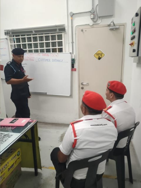 KSD Security instructor SO Faizal briefing two guards on customer-entrance procedures at the AEON Falim security training