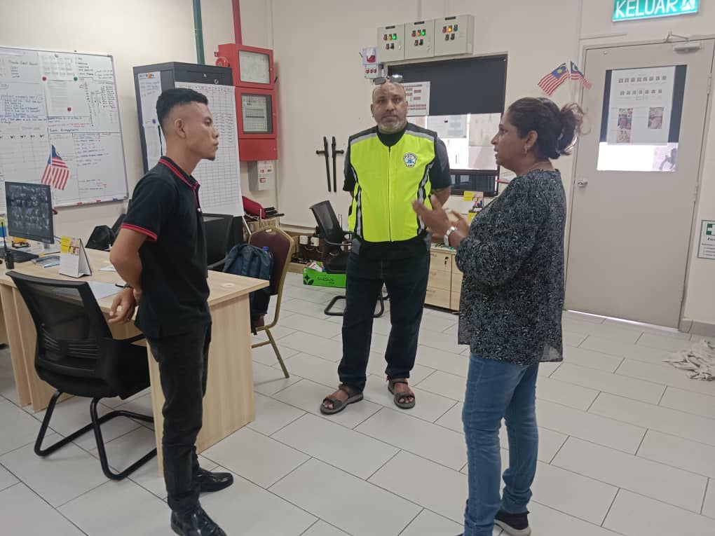 KSD Security supervisor in a hi-vis vest briefing staff in a site control room with monitoring boards and fire alarm panels.
